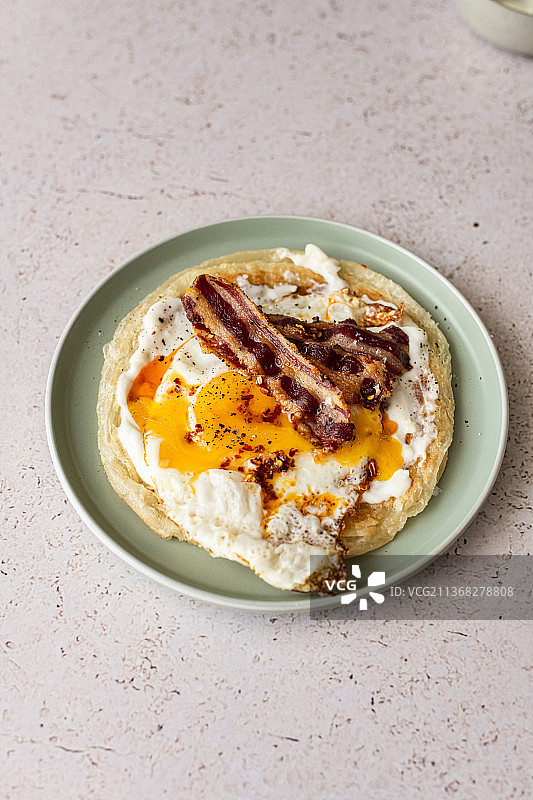 印度抛饼配蒜蓉酸奶、流黄煎蛋、培根和辣椒油图片素材