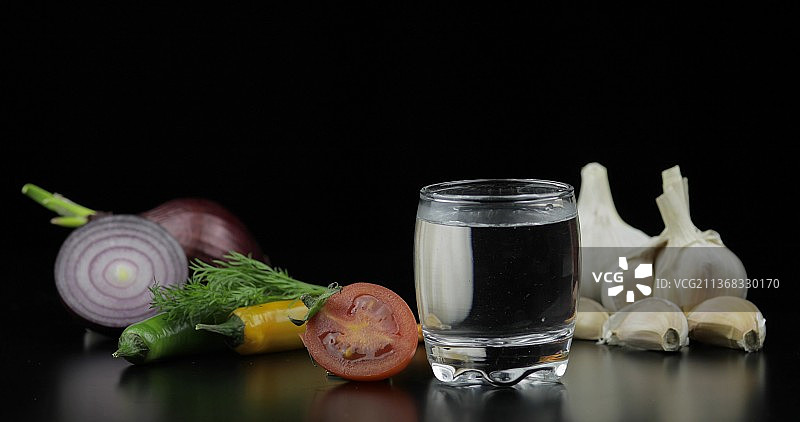 蔬菜背景上的小杯伏特加酒精饮品图片素材