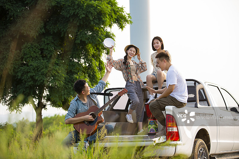 青年男女户外旅行，在皮卡车上开派对，弹奏乐器跳舞嬉戏图片素材