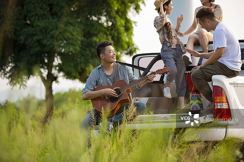 青年男女户外旅行，在皮卡车上开派对，弹奏乐器跳舞嬉戏图片素材