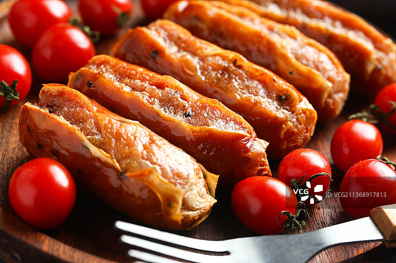 烤肠和圣女果放在木盘里图片素材