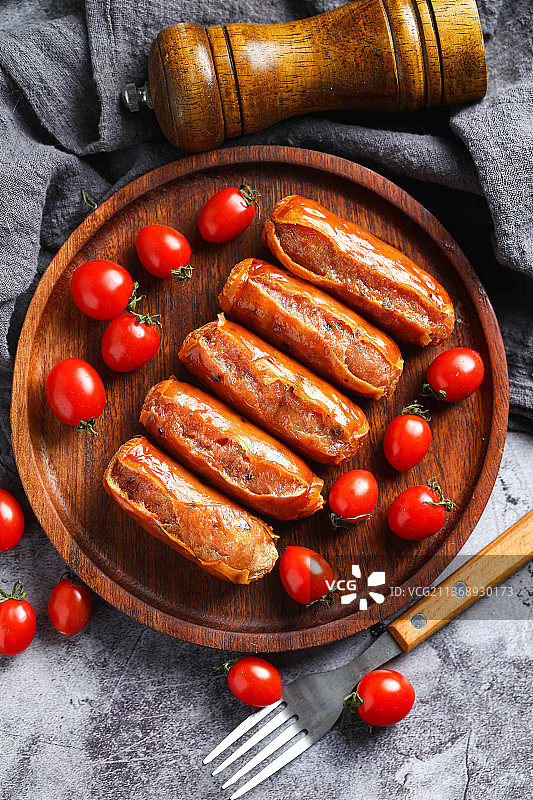 烤肠和圣女果放在木盘里图片素材