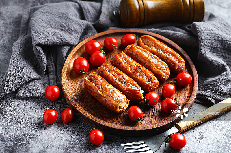 烤肠和圣女果放在木盘里图片素材