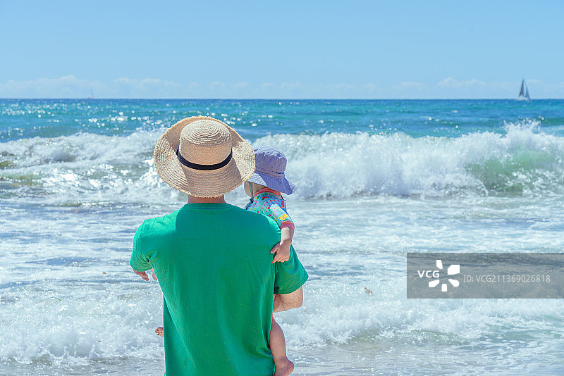 大海边上抱小孩的旅行者图片素材