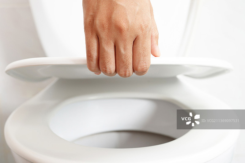 男人打开马桶盖，露出卫生间里的马桶图片素材