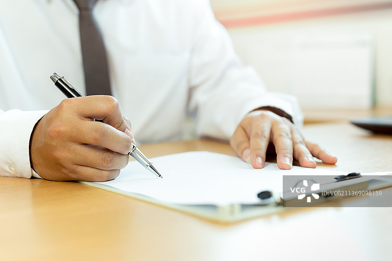 在办公桌上用笔签署合同文件的商人图片素材