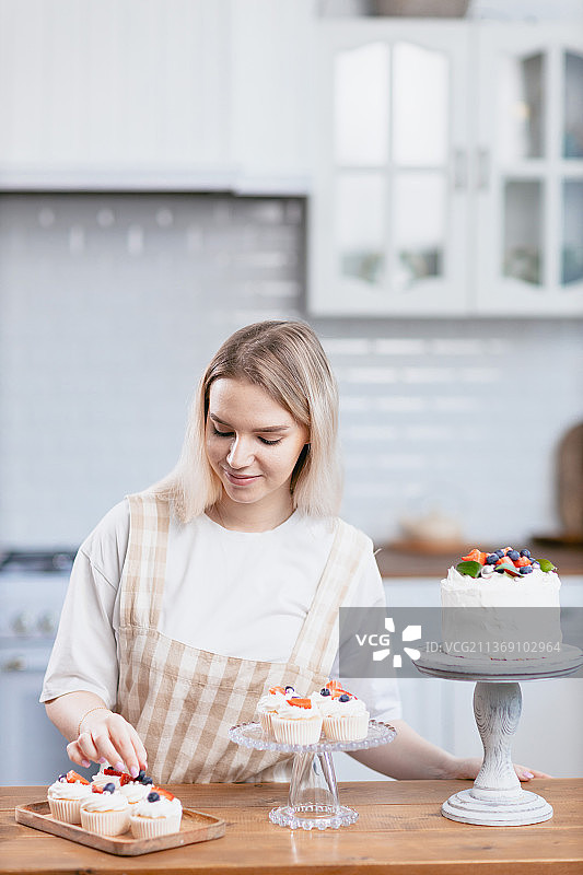 厨房里拿着蛋糕的年轻白人糕点师图片素材