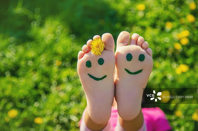 草地上的孩子脚画着微笑，选择性聚焦图片素材