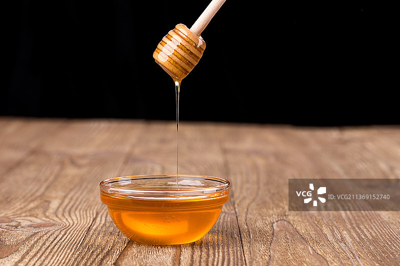 蜂蜜滴入罐中，桌上蜂蜜棒特写图片素材