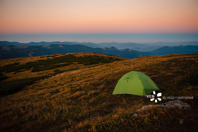 山顶上拥有壮丽景色的绿色露营帐篷图片素材