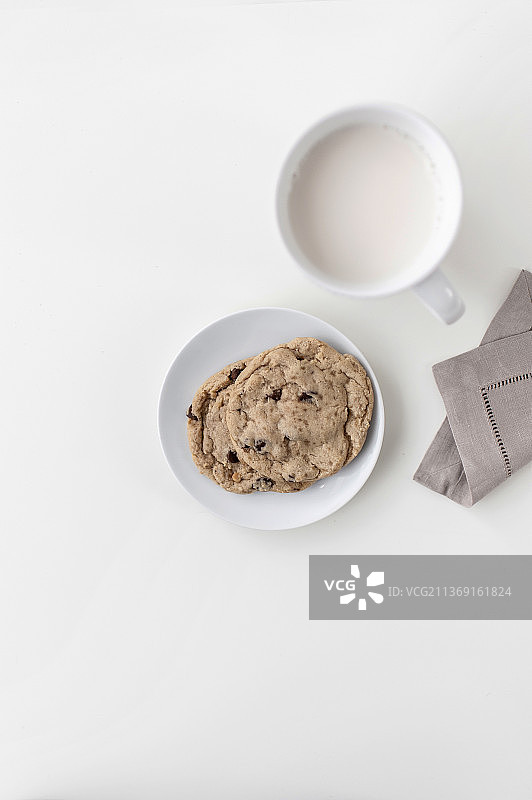 白色台面上放着一杯加牛奶的白色马克杯，旁边放着餐巾图片素材