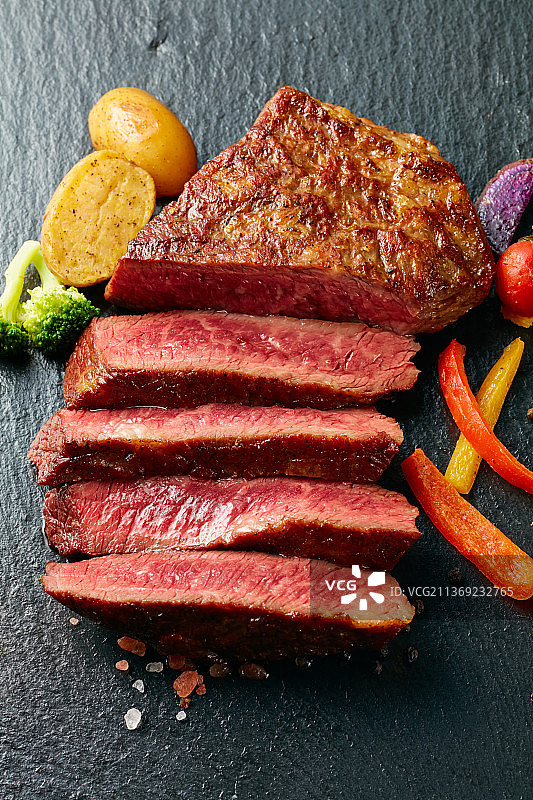 黑色石板背景的熟牛排图片素材