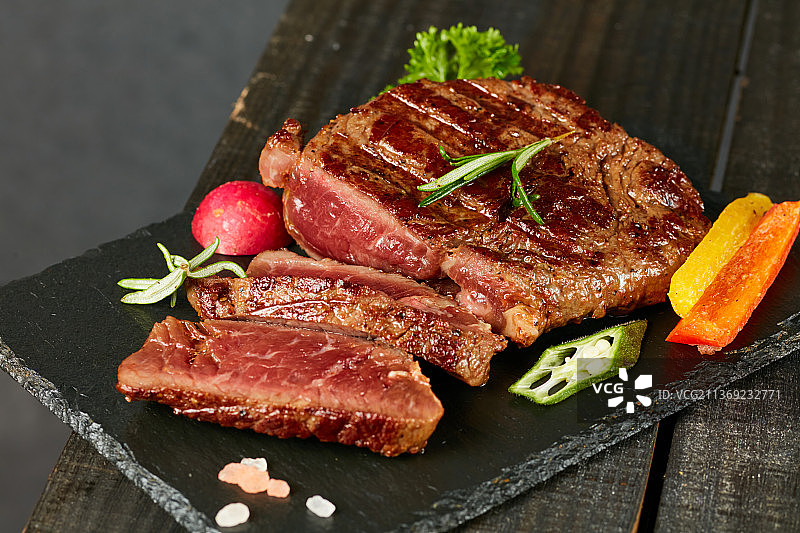 黑色石板背景的熟牛排图片素材