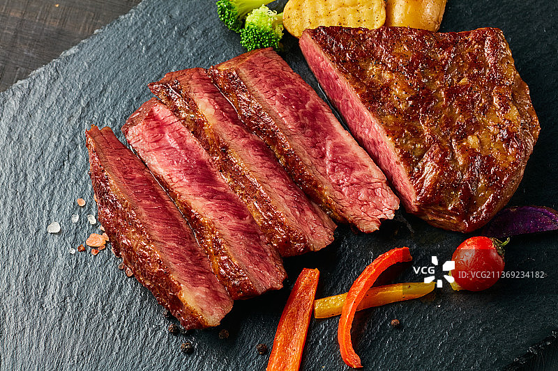 黑色石板背景的熟牛排图片素材