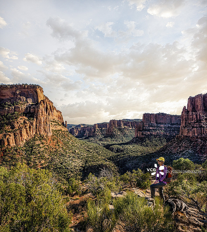 女徒步旅行者和她的狗俯瞰着红岩峡谷图片素材