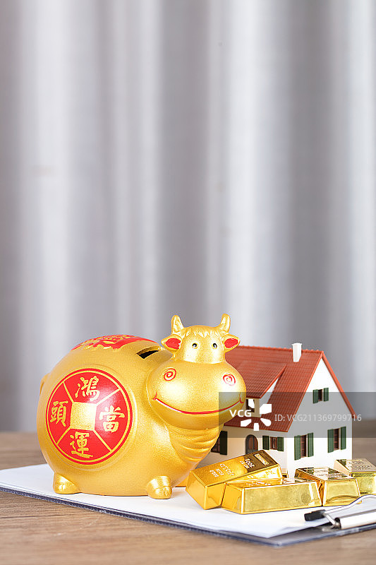 房屋模型旁的金牛存钱罐和金条图片素材