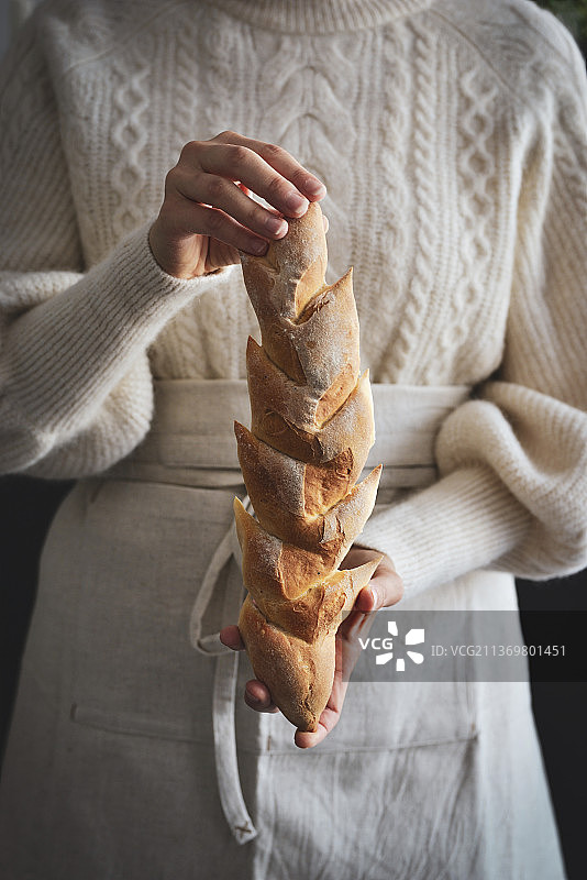 一个女人穿着围裙拿着烤好的法棍面包图片素材