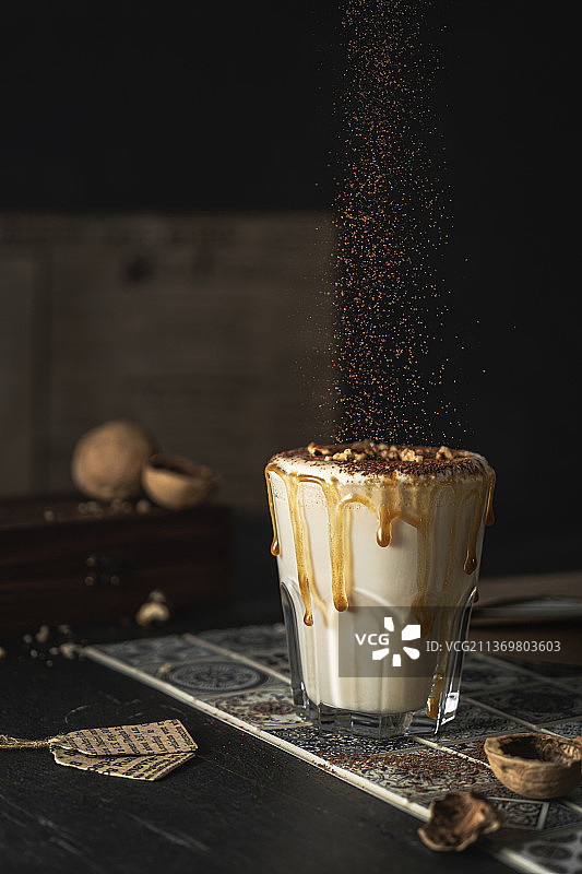 焦糖奶昔，配焦糖滴、坚果和可可粉图片素材