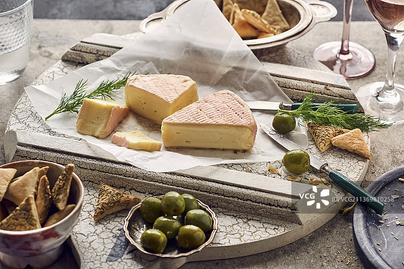 木板上的芒斯特干酪配绿色橄榄和迷迭香饼干图片素材