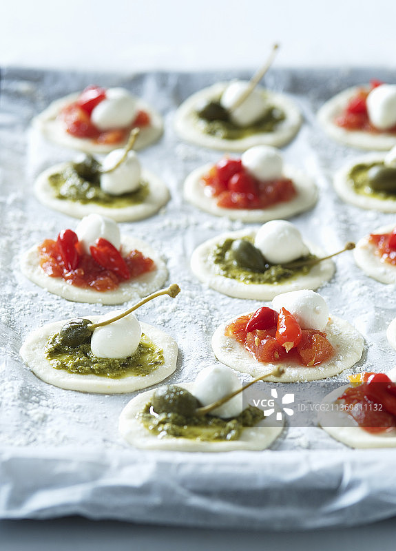 含番茄、香蒜酱、刺山柑和迷你马苏里拉奶酪的迷你披萨（未烘烤）图片素材