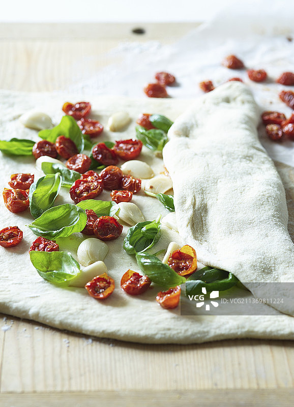 准备披萨口袋，配烤箱烘干的樱桃番茄、大蒜和罗勒图片素材