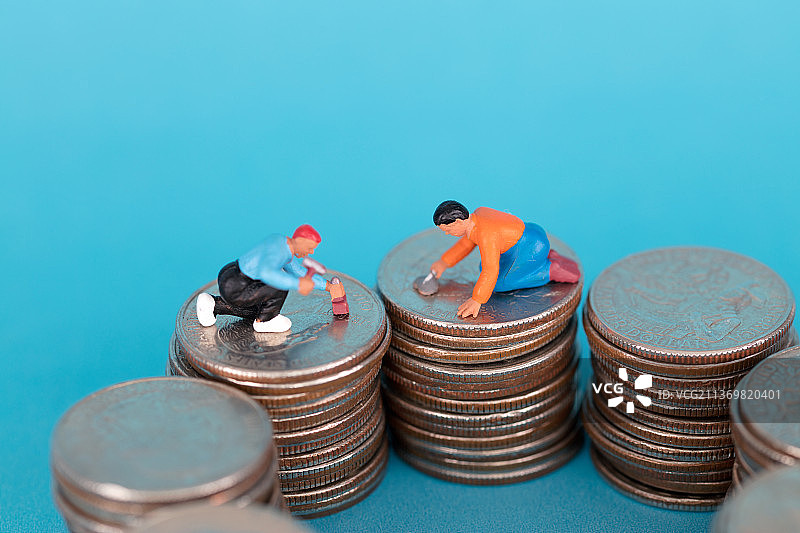 微缩的工人人偶在修理硬币图片素材