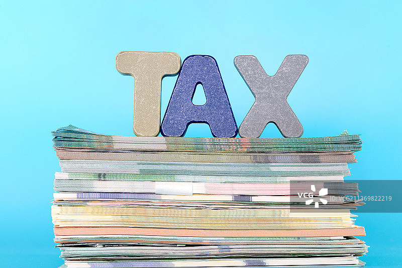 一沓各式各样的钞票和立体字母组成的TAX图片素材