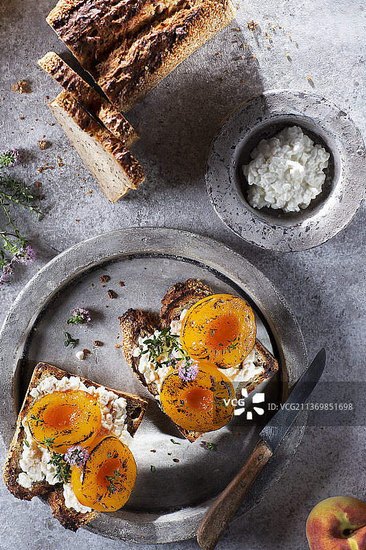 搭配粗粒奶油干酪和烤桃子的三 grain 面包图片素材