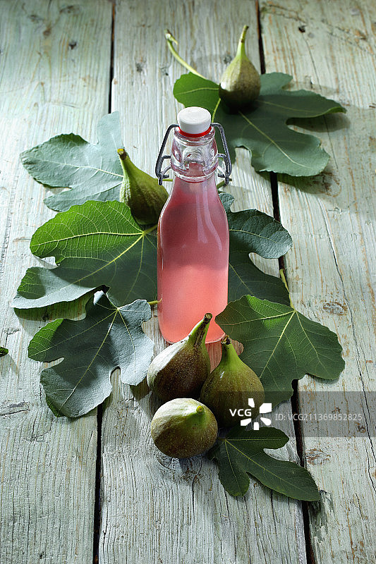 新鲜无花果和无花果叶环绕的无花果利口酒图片素材