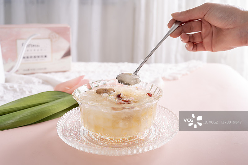 桌子上女性的手和玻璃碗装的银耳羹图片素材