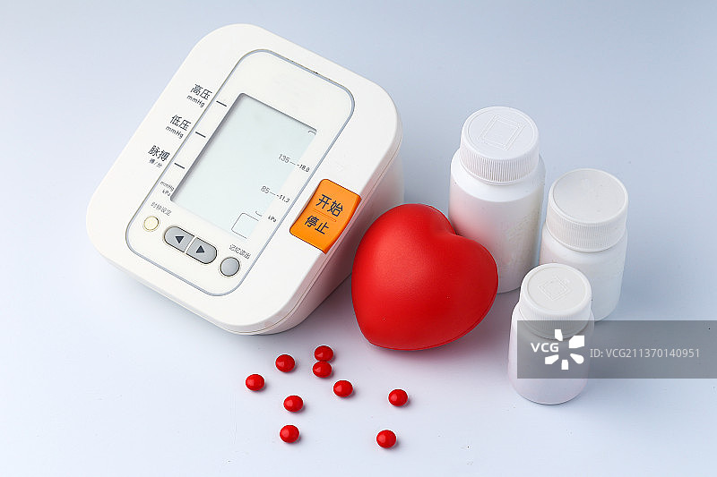 电子血压计和红心药瓶在白色背景图片素材