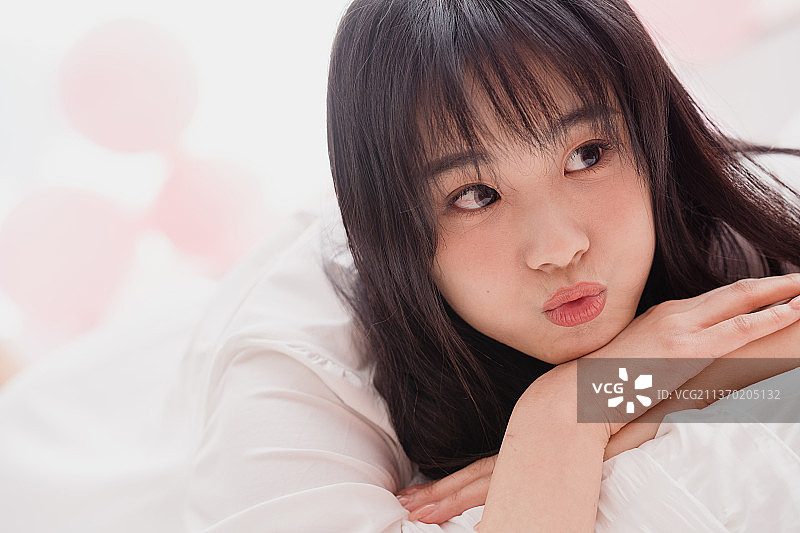 年轻的漂亮女孩趴在床上图片素材