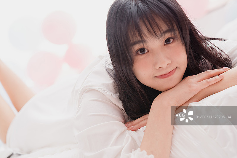 年轻的漂亮女孩趴在床上图片素材