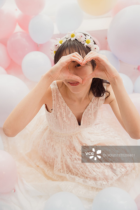 穿着婚纱的女孩坐在床上比心图片素材