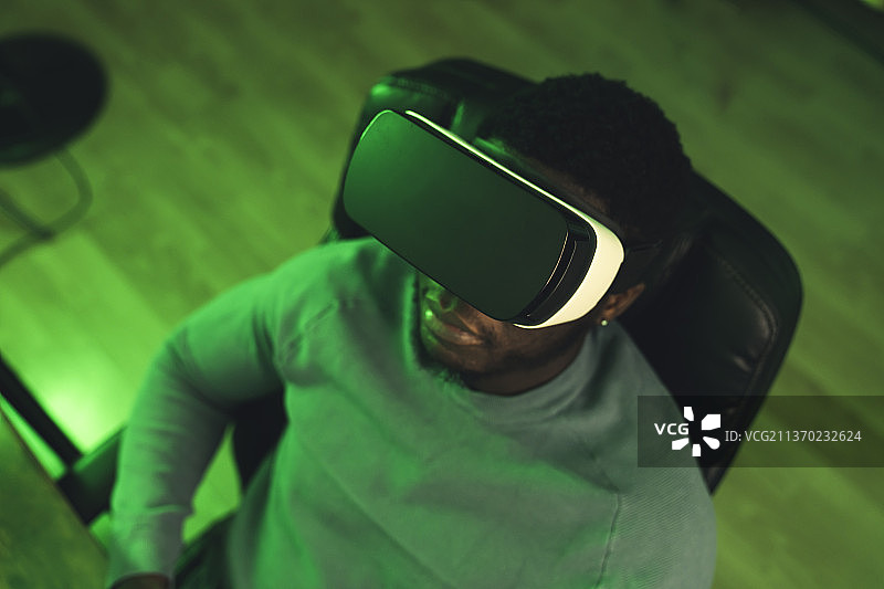 黑人男子坐着玩VR游戏 - 霓虹灯肖像照图片素材