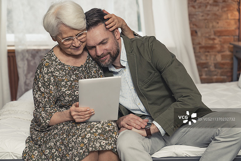 现代退休老妇拥抱并安慰她的中年儿子图片素材