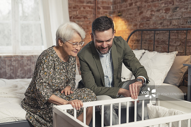 年长的白人母亲和儿子高兴地看着新生儿图片素材