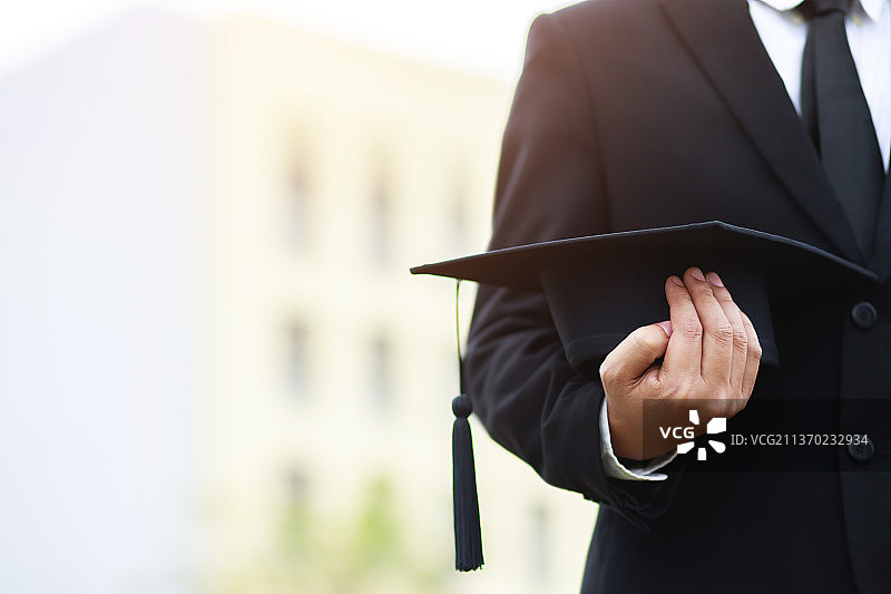 年轻男子毕业照背影，商人手持平板电脑图片素材