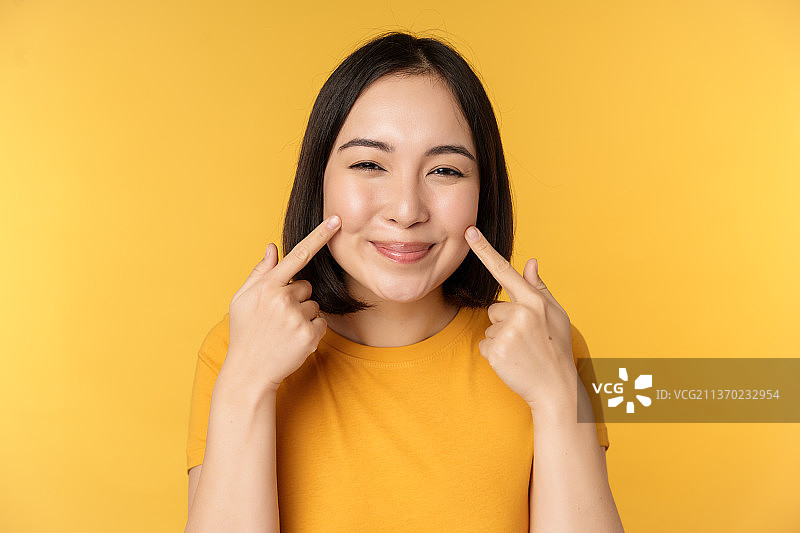 可爱的亚洲女孩展示她的酒窝和微笑的特写图片素材