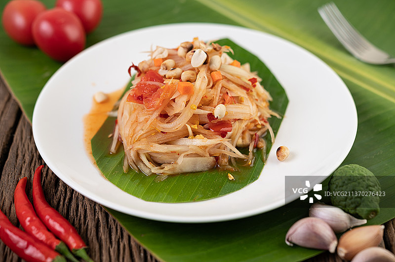 白色盘子里放在香蕉叶上的泰式木瓜沙拉和酸橙图片素材