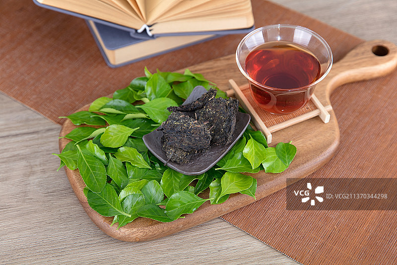 砧板上的茶水和茶叶和铺着的绿叶图片素材