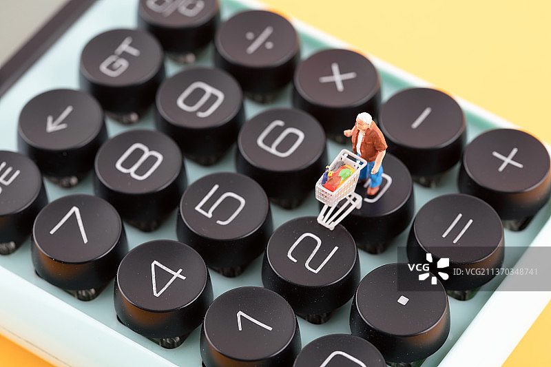 计算器键盘上特写推购物车购物的人偶图片素材