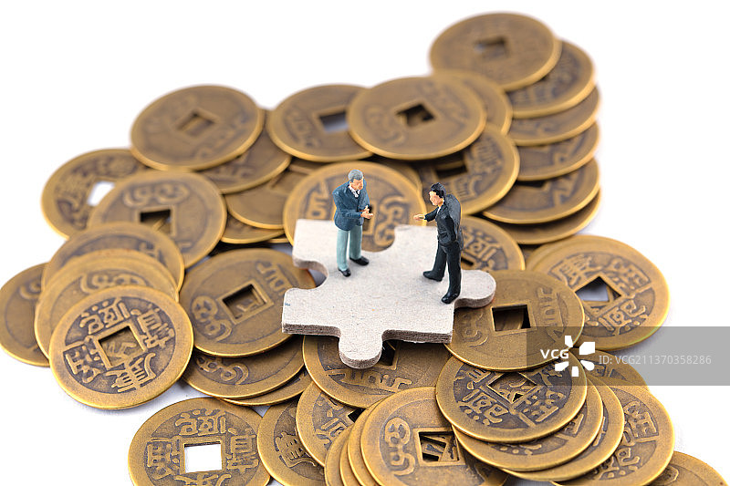 一堆铜钱上合作的商人图片素材