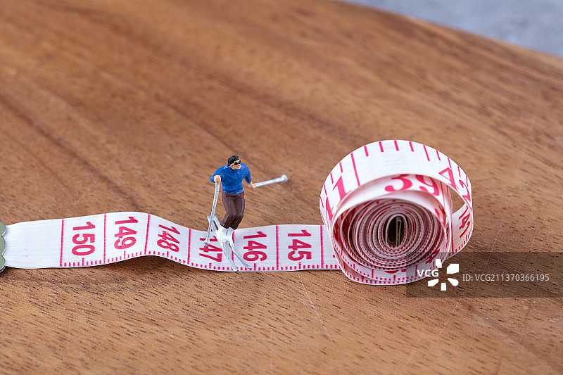 测量腰围的软尺和滑雪运动的人偶图片素材