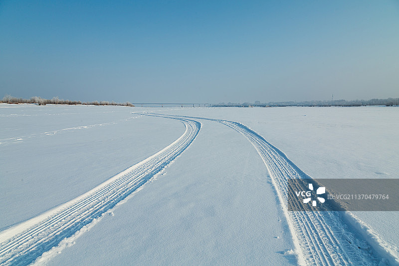 冬天平坦雪地上的汽车轮胎印，雪地上的车辙图片素材
