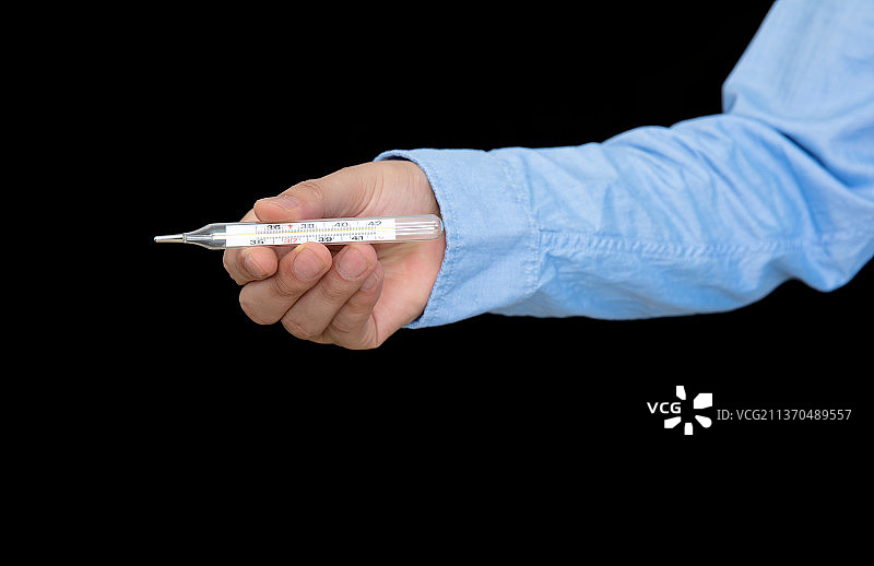 手拿水银体温计在黑背景前图片素材