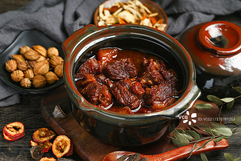 砂锅里的炖牛肉和调料放在木板上图片素材