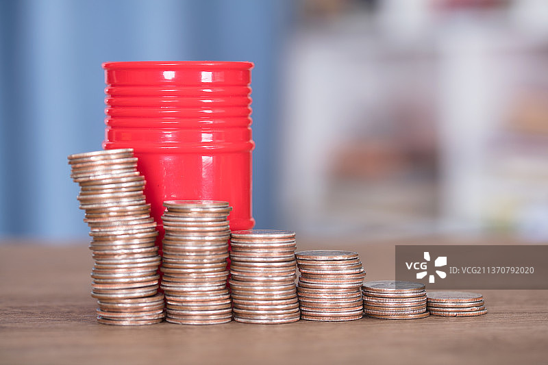 一排递减的美元硬币和石油桶图片素材