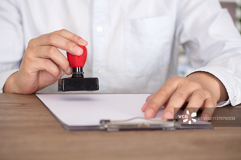 穿着衬衣的工作人员在文件上加盖公章图片素材