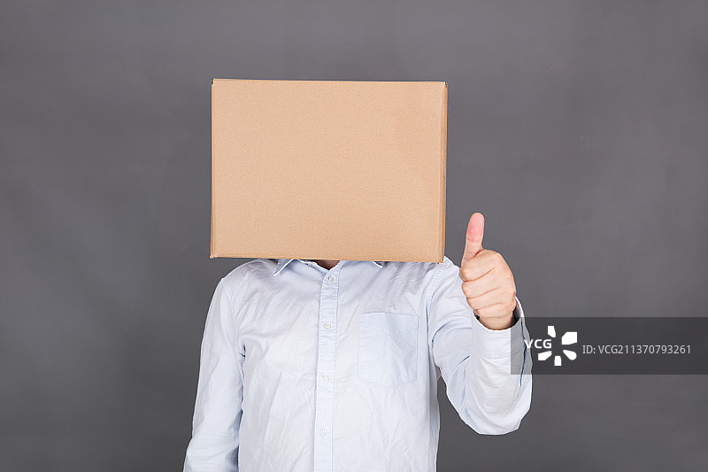 头戴纸箱子的男士伸手竖起大拇指图片素材